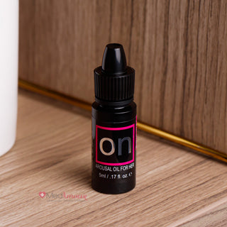 Small black bottle labeled 'on' on a wooden surface with a plant in the background